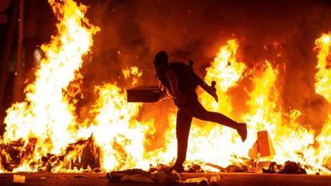 Un villano alimentando el fuego con cartones en Barcelona. (Foto www.20mi8nutos.es - EFE)