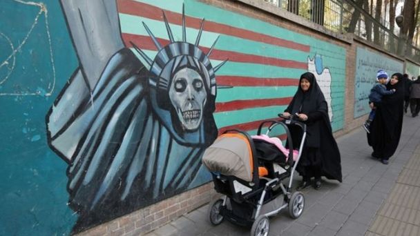 Una mujer iraní camina junto a un grafiti de referencia en la antigua embajada de Estados Unidos en Irán. / AFP. (www.paginasiete.bo)